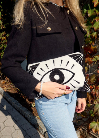 Model holding a large cotton clutch bag with a black evil eye design made in Greece. Handbag accessories with Greek mati design. Loomed cotton clutch bag