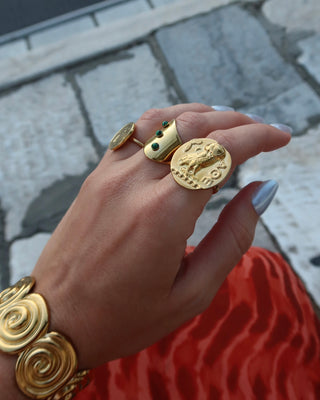Hand wearing gold jewelry including a gold athenian tetradrachm coin ring with Ancient Greek goddess Athena's owl, a symbol of wisdom. Owl ring made in Greece, Greek jewelry