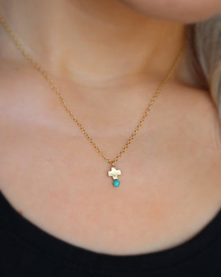 Gold-plated sterling silver mini cross necklace with a turquoise blue bead at the bottom, made in Greece. 