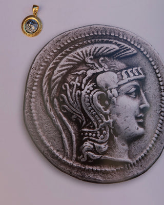 Silver replica ancient Greek coin featuring Athena, the Greek goddess of wisdom wearing a helmet, surrounded by an 18k gold-plated Greek key meander frame. Greek mythology jewelry