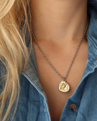 Woman wearing a silver coin pendant necklace with Athena's Owl of Wisdom, a replica of an ancient Greek Athenian tetradrachm coin that is silver with a gold owl, two-tone mixed metal necklace made in Greece on an infinity s-link chain