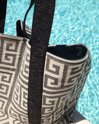 Tote bag with greek key meander pattern and black metallic silver strap by a pool