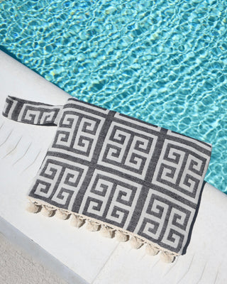 Black and cream/white greek key meander print clutch bag with pom pom trim and wet/dry water-resistant interior for the beach, made in Greece. Aelia Anna wet/dry bag at the pool