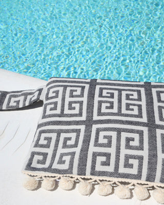 Black and cream/white greek key meander print clutch bag with pom pom trim and wet/dry water-resistant interior for the beach, made in Greece. Aelia Anna wet/dry bag at the pool