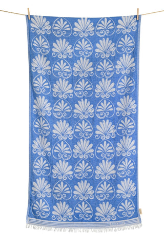 Blue cotton beach towel with white Anthemion pattern hanging on a line