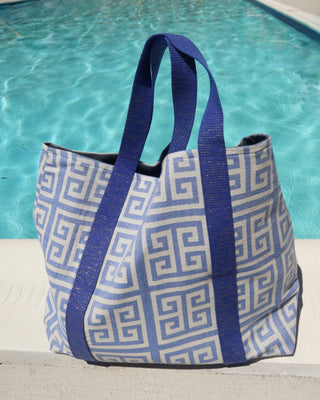 Blue and white greek key print beach bag in front of a pool