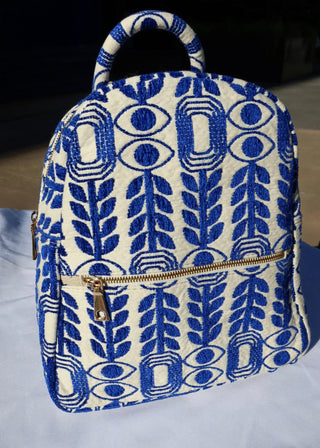 Woven cotton backpacks made in Greece with blue and white designs. Evil eye and olive leaf backpack handmade with gold zippers. Artisinal handbags handcrafted in Greece