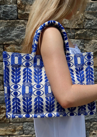 Large blue and white tote bag made in Greece by artisans using looms. Greek motif design with evil eyes, olive branches, and modern shapes. Handmade fashion shopper bag, beach bag