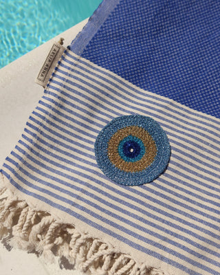 Blue and off-white striped cotton pestemal towel with an embroidered metallic evil eye and fringe trim made in Greece, Greek beach towel by Aelia Anna