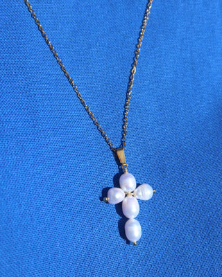 Freshwater earl cross necklace with a gold colored chain on a blue background made in Greece. Greek pearl cross necklace
