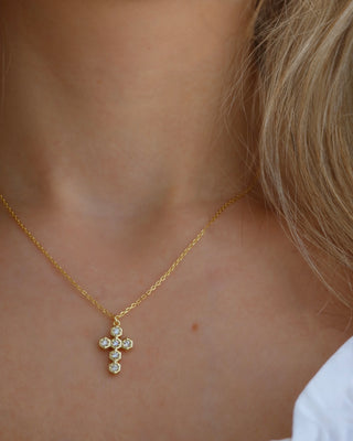 Gold-plated necklace with a cubic zirconia cross pendant on a woman's neck. Greek cross necklace, jewelry made in Greece