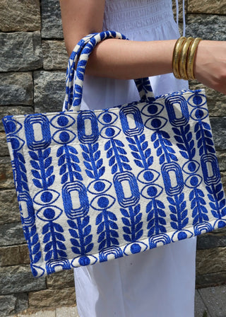 Large blue and white tote bag made in Greece by artisans using looms. Greek motif design with evil eyes, olive branches, and modern shapes. Handmade fashion shopper bag, beach bag