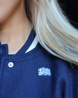 Woman wearing a Greek flag metal lapel pin on her blue jacket as a fashion accessory