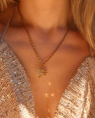 Woman wearing a gold spiral sun pendant necklace made in Greece, Greek jewelry