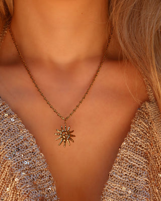 Woman wearing a gold spiral sun pendant necklace made in Greece, Greek jewelry