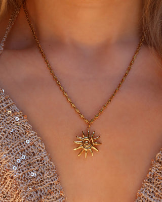 Woman wearing a gold spiral sun pendant necklace made in Greece, Greek jewelry
