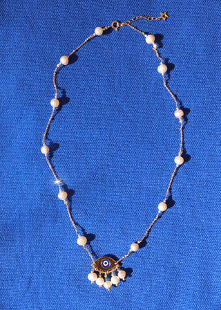Gold-plated necklace made in Greece with freshwater pearls and an evil eye pendant with a blue quartz stone at Aegean Essence