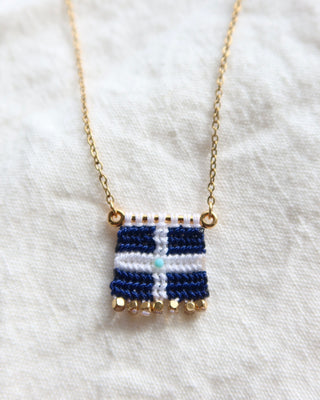 A navy blue and white woven macrame Greek flag necklace with a gold chain and gold bead details made in Greece. Vintage Hellenic Republic flag necklace with turquoise stone and gold embellishments
