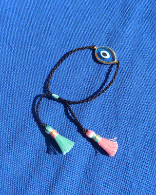 a turquoise blue Murano glass 18k gold plated evil eye bracelet with an adjustable black woven design and a pink and mint green tassels made in Greece, Greek evil eye jewelry