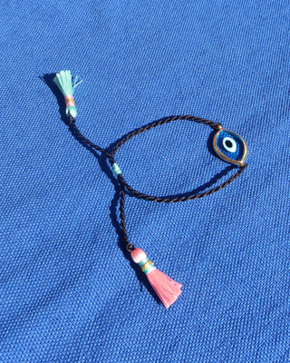a turquoise blue Murano glass 18k gold plated evil eye bracelet with an adjustable black woven design and a pink and mint green tassels made in Greece, Greek evil eye jewelry