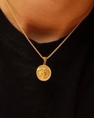 An 18k gold-plated sterling silver 925 rope chain necklace with a round medallion pendant featuring a Medusa design, worn by a person wearing a black shirt. Greek mythology jewelry