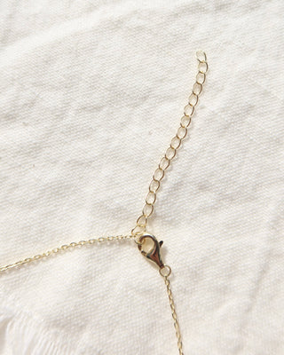 Gold necklace with a lobster claw clasp on a white fabric background