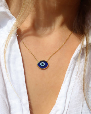Woman wearing a dark blue Murano glass evil eye necklace with a delicate gold-plated sterling silver chain made in Greece