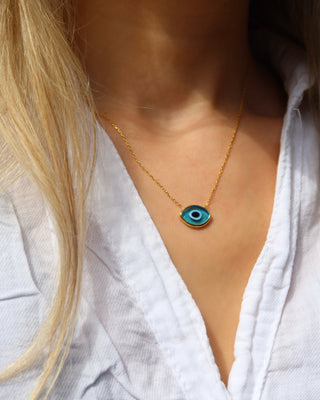 Woman wearing a light blue turquoise Murano glass evil eye necklace with a delicate gold-plated sterling silver chain made in Greece