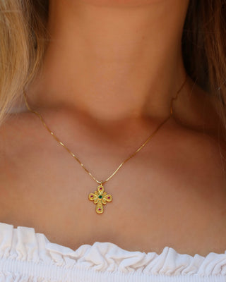 Woman wearing a 14k gold-plated sterling silver 925 Byzantine style cross necklace with an emerald and rubies made in Greece