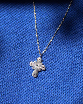 The back of a sterling silver 925 cross pendant necklace on a blue background