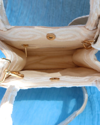 Cotton canvas interior of Cream/off-white handbag with two top handles and a crossbody strap with a white eye-shaped wave print woven cotton, made in Greece. Marabu bag worn by Lily Collins and Ashley Park in Emily in Paris Mykonos handbag brand
