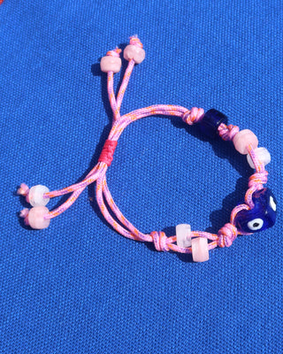 Pink adjustable woven rope bracelet with blue evil eye beads made in Greece