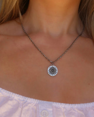 Woman wearing a silver gold sunburst coin pendant necklace with an infinity chain made in Greece, ancient Greek coin jewelry