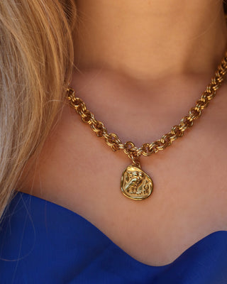 Woman wearing a gold statement necklace with a chunky chain and a gold tone Athenian tetradrachm replica Greek coin pendant with goddess Athena's owl of wisdom