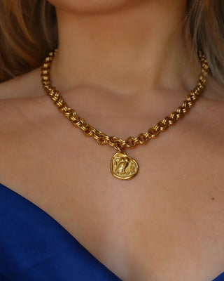 Woman wearing a gold statement necklace with a chunky chain and a gold tone Athenian tetradrachm replica Greek coin pendant with goddess Athena's owl of wisdom