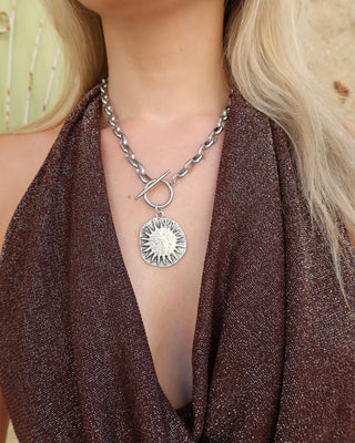 Person wearing a silver chunky chain necklace with a sun pendant and a toggle front made in Greece. Greek jewelry fashion necklace