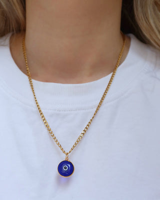 Gold chain necklace with a blue glass evil eye pendant on a woman. Greek mati jewelry, evil eye necklace made in Greece