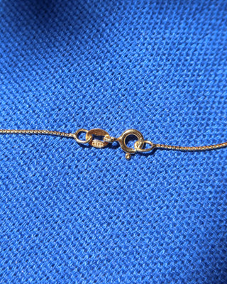 Spring ring clasp and gold chain necklace made in Greece on blue background