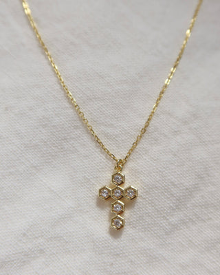 Gold-plated necklace with a hexangonal cubic zirconia cross pendant on a woman's neck. Greek cross necklace, jewelry made in Greece