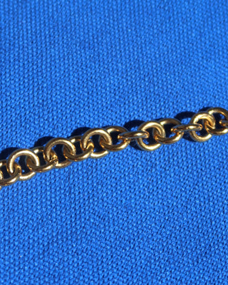 Gold necklace chunky chain on a blue fabric background