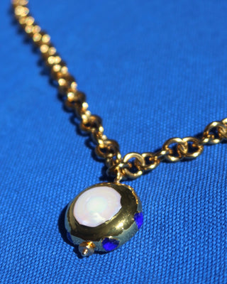 A gold chunky chain statement necklace with a jumbo freshwater pearl drop pendant with blue zircon stones surrounding it made in Greece. Greek jewelry