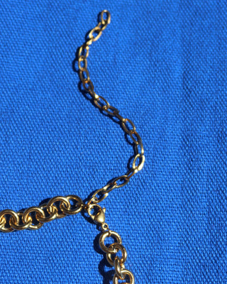 Gold necklace chain on a blue fabric background showing the extender and lobter claw clasp