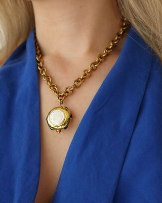 Woman wearing a gold chunky chain statement necklace with a jumbo freshwater pearl drop pendant with blue zircon stones surrounding it made in Greece. Greek jewelry
