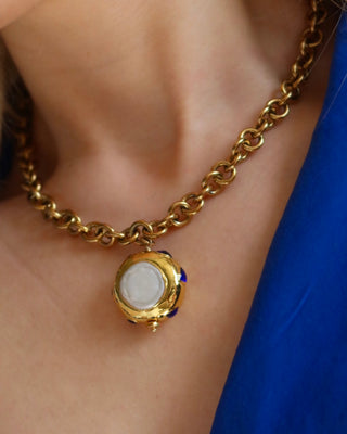Woman wearing a gold chunky chain statement necklace with a jumbo freshwater pearl drop pendant with blue zircon stones surrounding it made in Greece. Greek jewelry