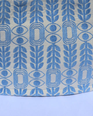 Light blue woven print with olive branches, evil eyes, and abstract geometic shapes