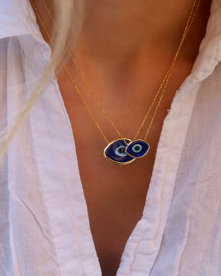 Woman wearing two gold-plated sterling silver necklace with a dark blue Murano glass evil eye pendants (one small and one large) made in Greece, Greek jewelry