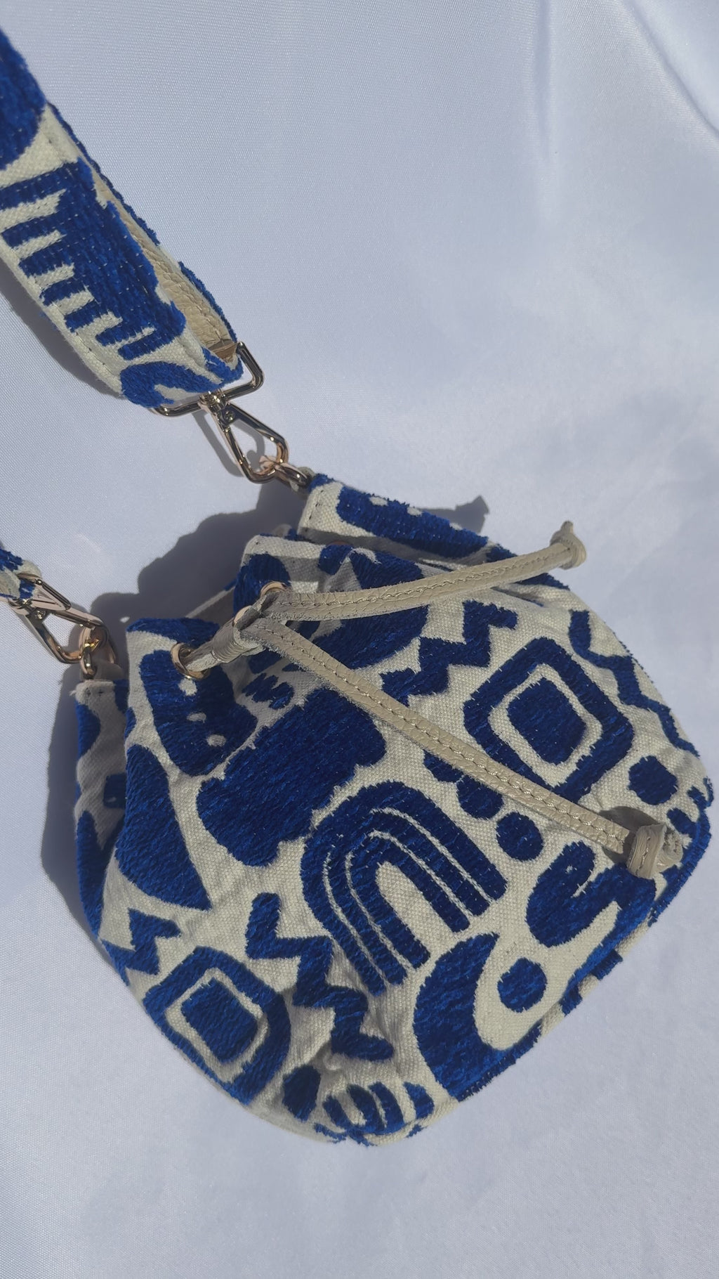 Blue and cream bucket crossbody bag with cute symbols like hearts, moons, eyes, and rainbows