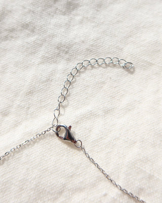 Silver chain necklace lobster claw clasp with extender on a white fabric background